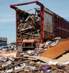 A large red truck drops off trash into a pile on the South Kent County Landfill.
